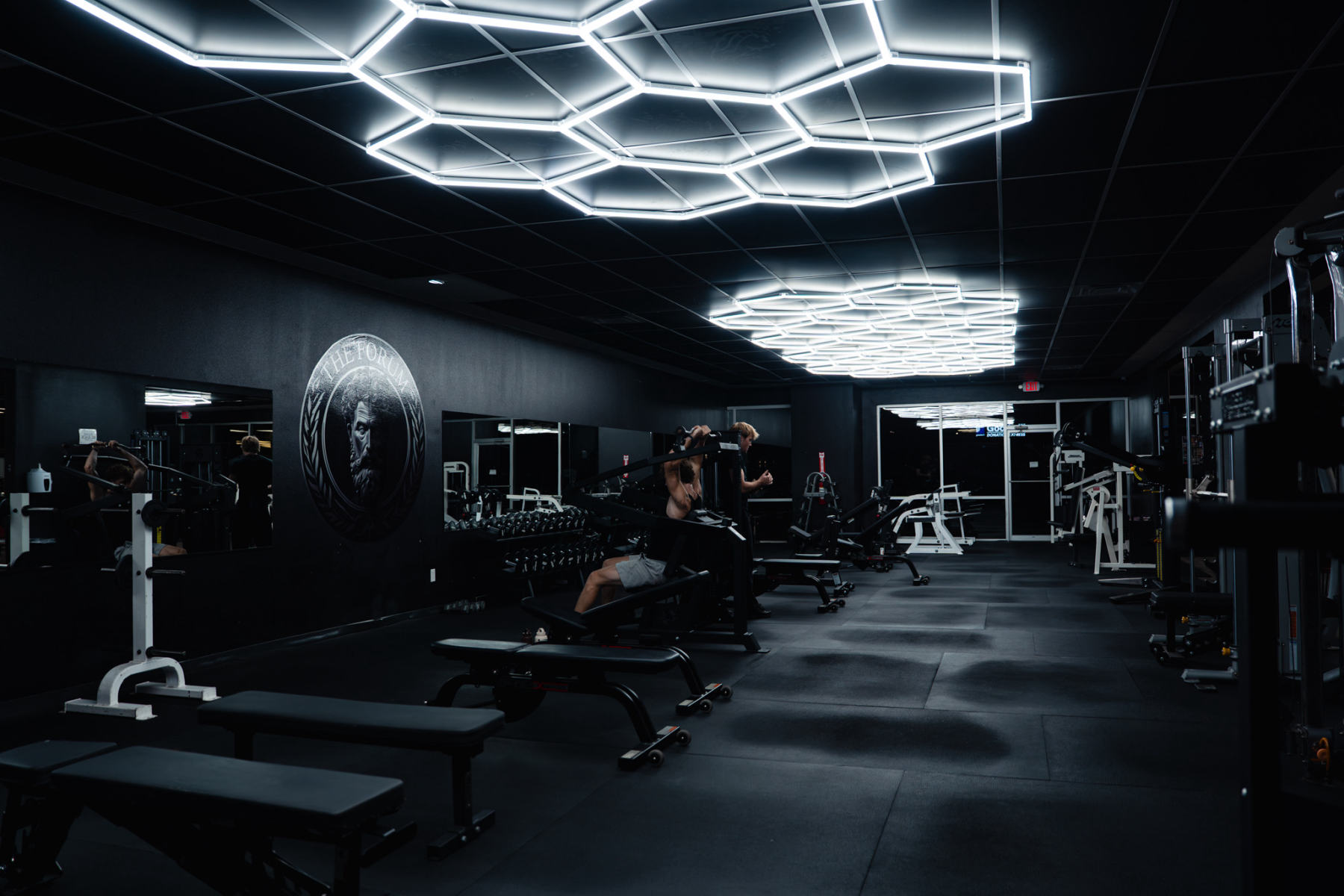 The Forum's free-weight floor beneath hexagon lighting
